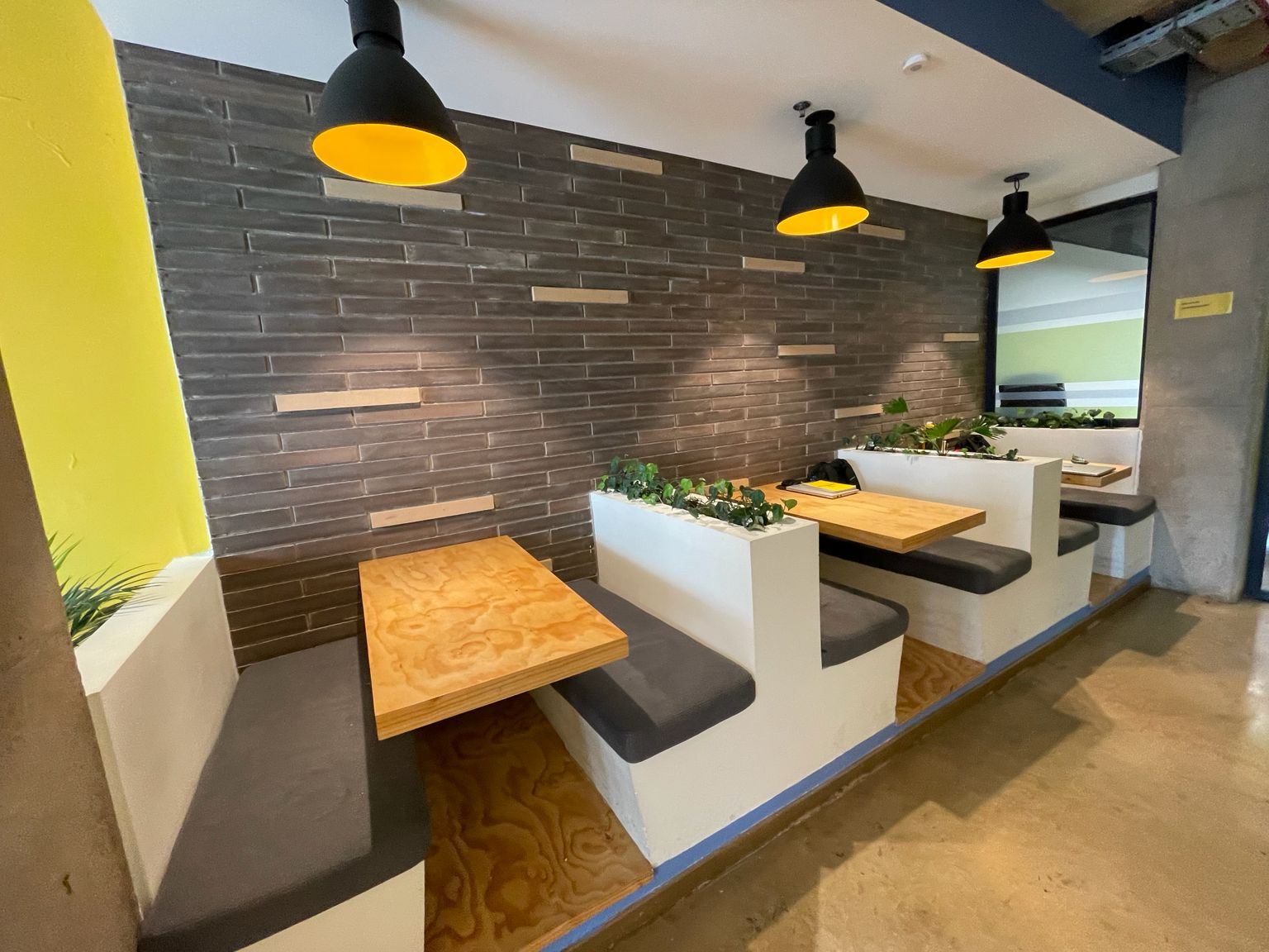 Nichos de comedor con bancas en obra blanca, mesas de madera y lámparas negras