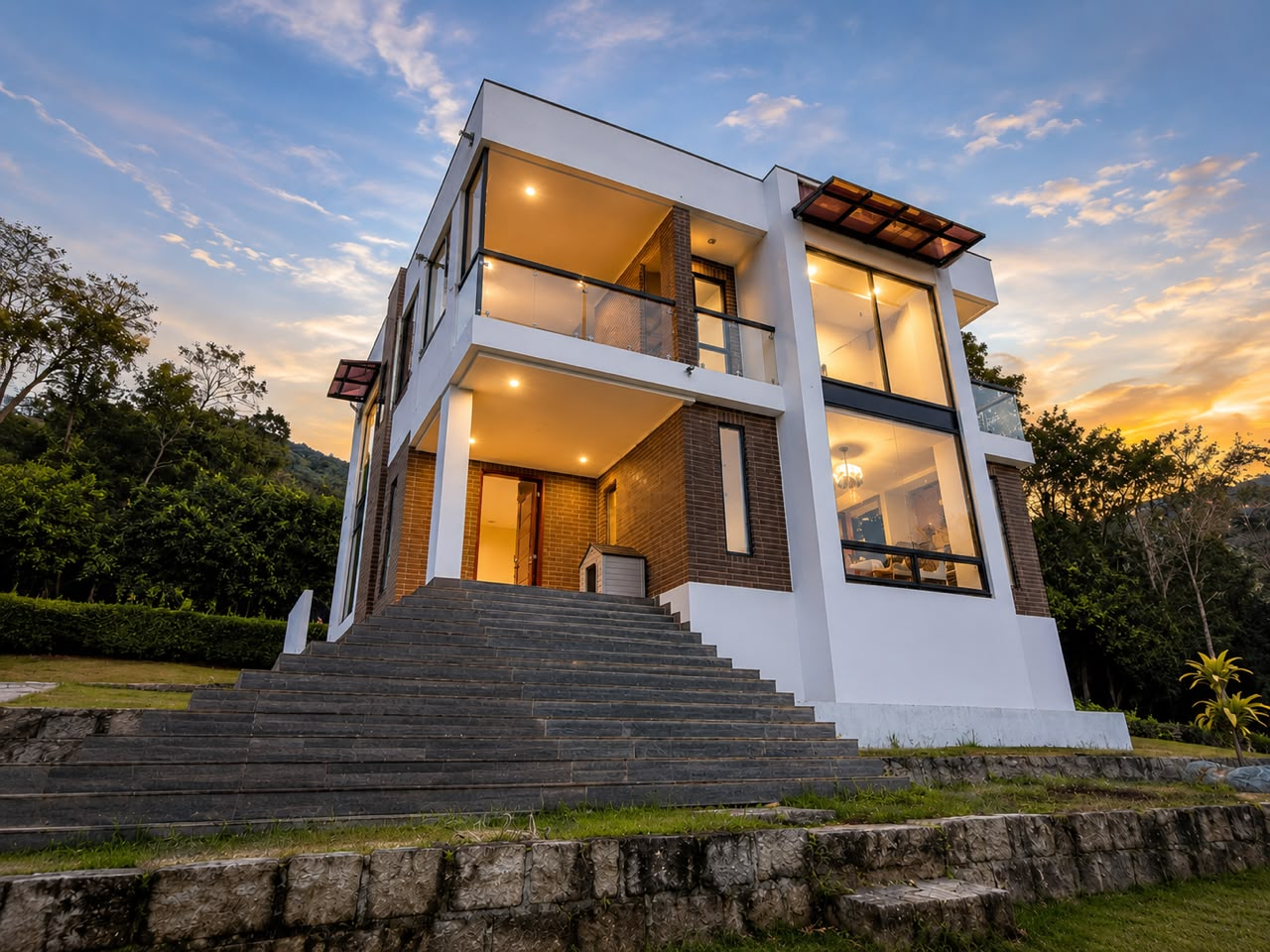Vivienda moderna de dos niveles al atardecer con fachada blanca y ventanales