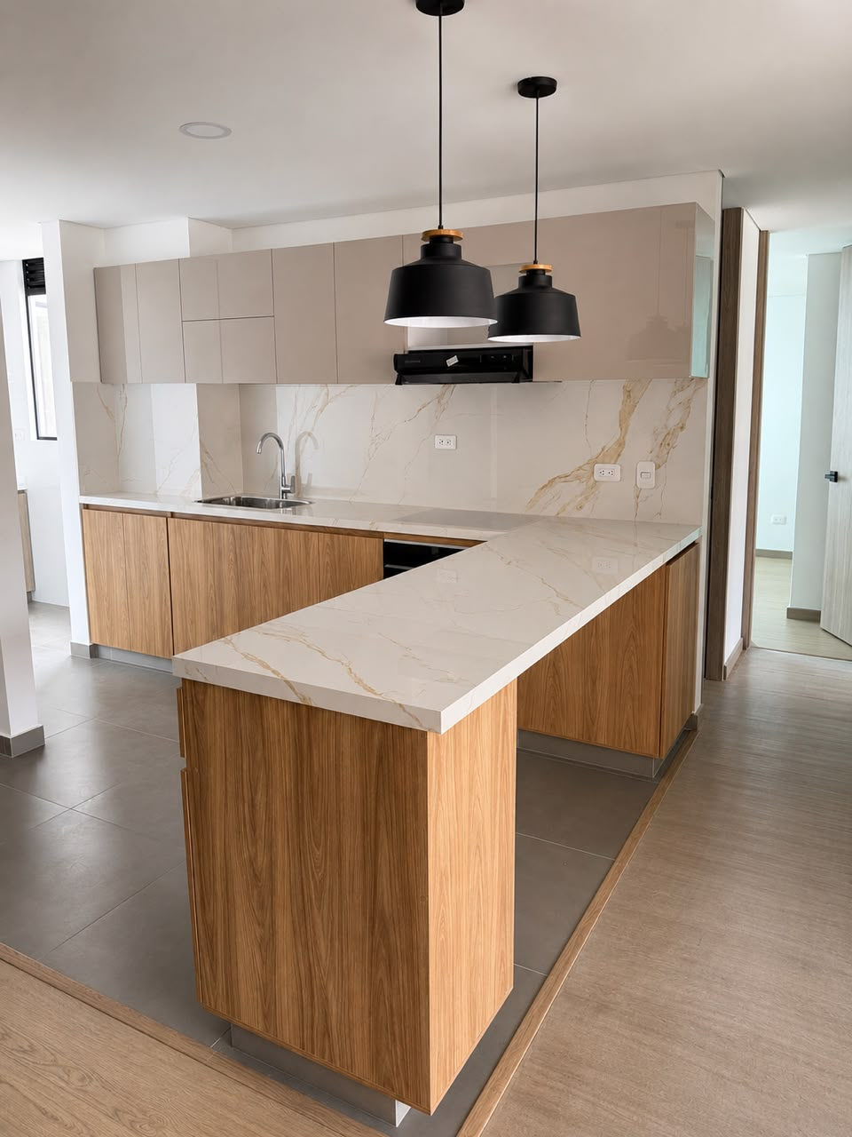 Cocina en madera con mesón blanco y lámparas colgantes negras