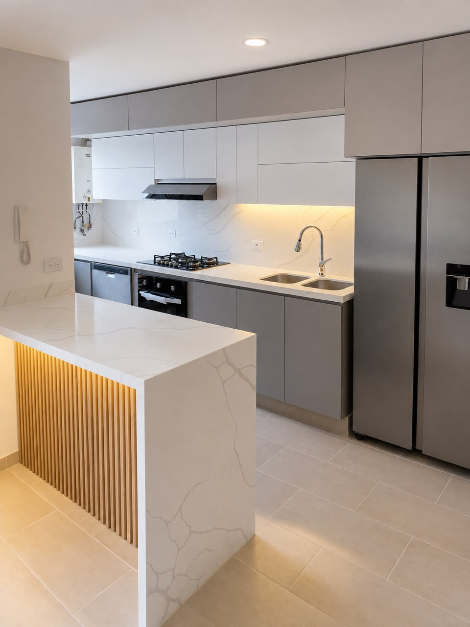 Cocina gris con isla en superficie blanca, iluminación cálida y detalle vertical en madera