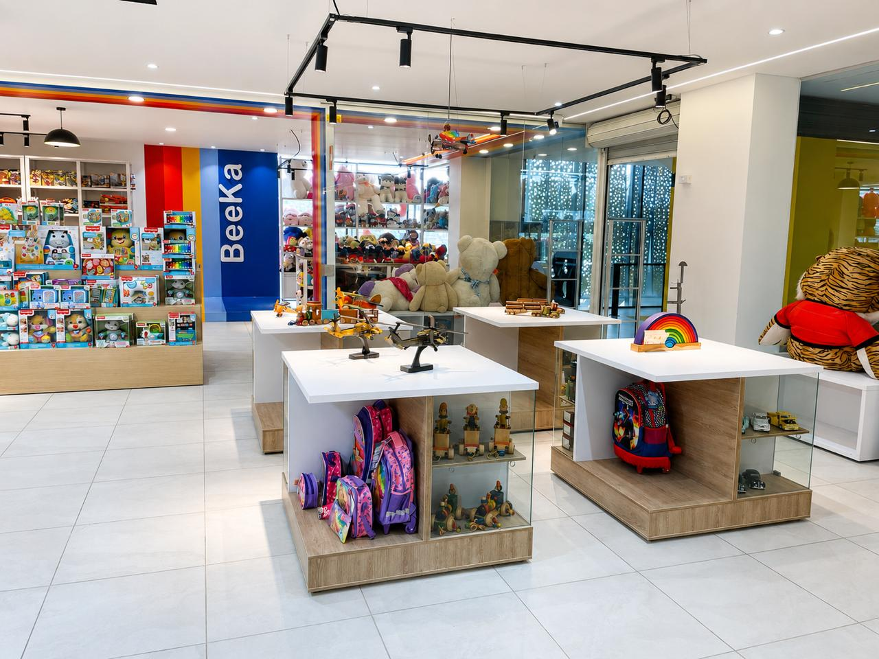 Local comercial de juguetería con mesas de exhibición blancas, góndolas e iluminación en riel